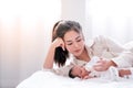 Portrait of young Asian mother give milk to her newborn baby on white bed with morning light Royalty Free Stock Photo