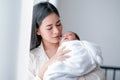 Portrait of young asian mother take care her newborn baby and holding on her chest in front of white curtain with morning light