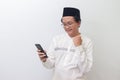 young Asian muslim man raising his fist, celebrating winning game or getting good news on his mobile phone. Isolated Royalty Free Stock Photo