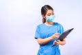 Portrait of young Asian nurse wearing surgical mask holding clipboard isolated on white background Royalty Free Stock Photo