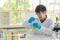 Portrait of young asian professional doctor scientist wearing glasses and blue rubber gloves holding chemical beaker flask glass