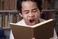 Portrait of young Asian student boy tired sleepy and yawning when reading a book, student tired when studying hard Royalty Free Stock Photo