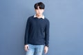 Portrait of Young Asian teenage cool hair stylish wearing blue sweater indicate blank space on blue navy wall background.