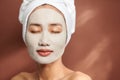 Portrait of young Asian wearing clay mask over brown background