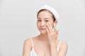 Portrait of young Asian woman applying cream on her face over white background Royalty Free Stock Photo