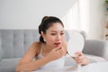 Portrait of Young Asian woman applying lipstick looking at mirror Royalty Free Stock Photo