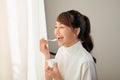 Portrait of young Asian woman eating yogurt behind the window Royalty Free Stock Photo