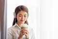 Young Asian woman enjoy listening to music with headphones and holding a hot cup of coffee, happy and relaxing time Royalty Free Stock Photo