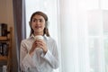 Young Asian woman enjoy listening to music with headphones and holding a hot cup of coffee, happy and relaxing time Royalty Free Stock Photo