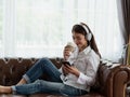 Young Asian woman enjoy listening to music with headphones and holding a hot cup of coffee  happy and relaxing time Royalty Free Stock Photo