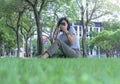 Portrait of young Asian woman enjoying and relaxing outdoors. Cheerful teenage female using a smartphone in the park Royalty Free Stock Photo