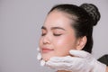 Portrait of a young asian woman getting a beauty medical treatment isolated over gray background