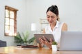 Portrait of young asian woman holding stylus pen while working on tablet computer at home Royalty Free Stock Photo