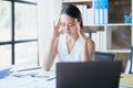 Portrait of a young Asian woman showing acute headache from sitting for a long time at work.