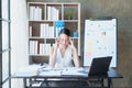 Portrait of a young Asian woman showing acute headache from sitting for a long time at work.