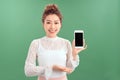 Portrait of young Asian woman showing her blank sreen mobile phone. Isolated over green background