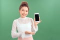 Portrait of young Asian woman showing her blank sreen mobile phone. Isolated over green background