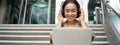 Portrait of young asian woman sitting with laptop and headphones, watching video, does online course on computer