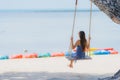 Portrait young asian woman sitting on swing rope and sea around beach sea ocean coconut palm tree for travel in holiday Royalty Free Stock Photo