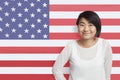 Portrait of young Asian woman smiling against American flag Royalty Free Stock Photo