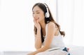 Portrait of young Asian woman smiling sitting in comfortable bed friendly listening to music in headphones enjoying singing song Royalty Free Stock Photo