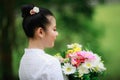 portrait of young asian woman standing wearing white traditional thai culture lanna dress style and flower on holding hand in Royalty Free Stock Photo