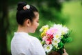 portrait of young asian woman standing wearing white traditional thai culture lanna dress style and flower on holding hand in Royalty Free Stock Photo