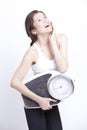 Portrait of young Asian woman with weight scale against white background Royalty Free Stock Photo
