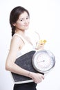 Portrait of young Asian woman with weight scale against white background Royalty Free Stock Photo