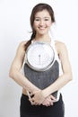 Portrait of young Asian woman with weight scale against white background Royalty Free Stock Photo