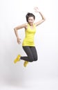 Portrait of young Asian woman in yellow tank top and leggings jumping against white background