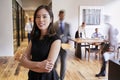 Portrait of young Asian woman in a busy modern workplace