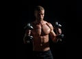 Portrait of young athlete doing exercise with dumbbell at isolated dark studio. Sexy sporty torso, man with dumbbells