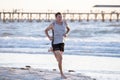 Athletic fit and strong runner man training on Summer sunset beach in sea shore running and fitness workout in sport and healthy l Royalty Free Stock Photo