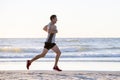 Athletic fit and strong runner man training on Summer sunset beach in sea shore running and fitness workout in sport and healthy l Royalty Free Stock Photo