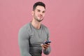 Portrait of a young athletic man mysteriously smiling, looking up and holding a smartphone. Royalty Free Stock Photo