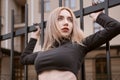 Portrait of young athletic woman in short black top. Sexy girl with long blonde heir near the fence Royalty Free Stock Photo