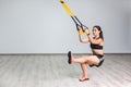 Portrait of young athletic woman in sportswear doing squat exercise, training legs and glutes muscular with fitness straps in the Royalty Free Stock Photo