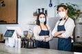 Portrait of young attractive Asian waiter and waitress wearing protective mask due to Covid-19 pandemic at cafe. Barista business Royalty Free Stock Photo