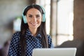Portrait of young attractive beautiful smiling cheerful good mood businesswoman in headphones at office workstation Royalty Free Stock Photo