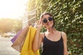 Portrait of young attractive brown-haired european woman in sun glasses and black clothes smiling in camera, holding big Royalty Free Stock Photo