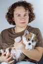 Portrait of young attractive brown-haired woman in T-shirt, holding funny fluffy velshkorgi puppy in her hands,. Royalty Free Stock Photo