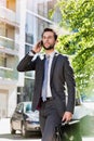 Portrait of young attractive businessman walking while talking on smartphone Royalty Free Stock Photo