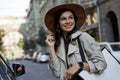 Portrait of a young attractive caucasian woman in hat with shopping bag looking aside and smiling while standing on the Royalty Free Stock Photo