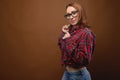 Portrait of a young attractive Caucasian woman in a red shirt and glasses on a brown background. Advertising glasses for Royalty Free Stock Photo