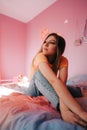 Portrait of young attractive cheerful woman sitting in a bedroom with pink walls Royalty Free Stock Photo