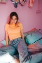 Portrait of young attractive cheerful woman sitting in a bedroom with pink walls Royalty Free Stock Photo