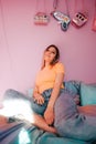 Portrait of young attractive cheerful woman sitting in a bedroom with pink walls Royalty Free Stock Photo