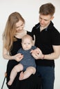 Portrait of young attractive family in dark clothes with plump cherubic baby infant toddler stand on white background.