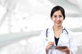Portrait of young attractive female asian doctor or physician smiling and holding tablet and stethoscope medical equipment looking
